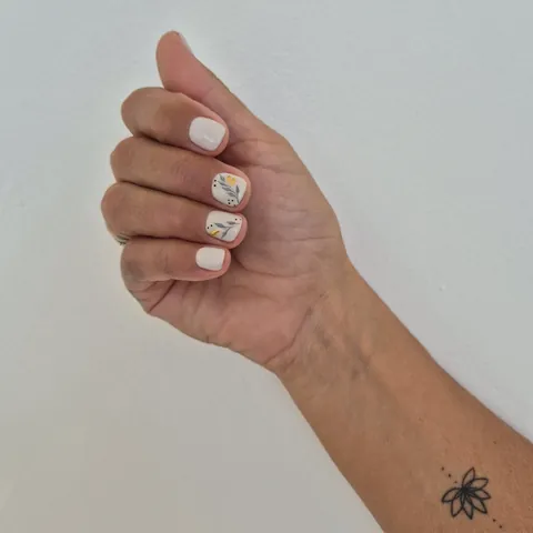 Uñas cortas en blanco roto con hojas grises y pan de oro