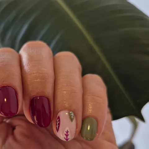 Uñas en burdeos y verde oliva con hojas pintadas a mano