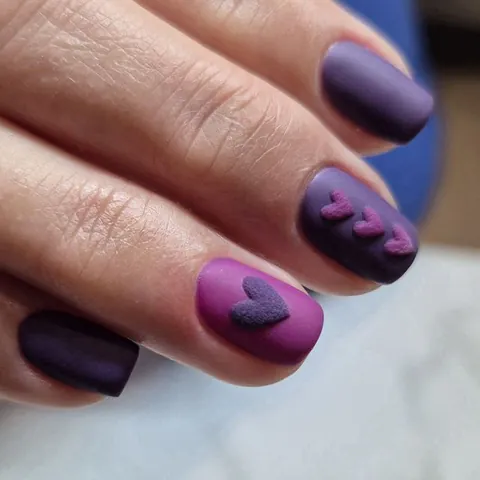 Manicura en morado mate con corazones de efecto terciopelo