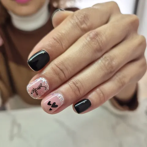 Uñas en negro y rosa con la palabra smile, corazones y láminas plateadas