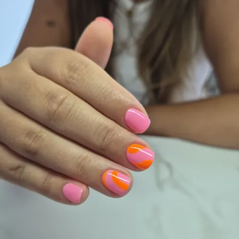 Uñas cortas en rosa chicle con ondas en naranja
