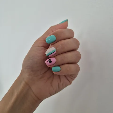 Uñas en turquesa y rosa con un corazón dibujado en negro